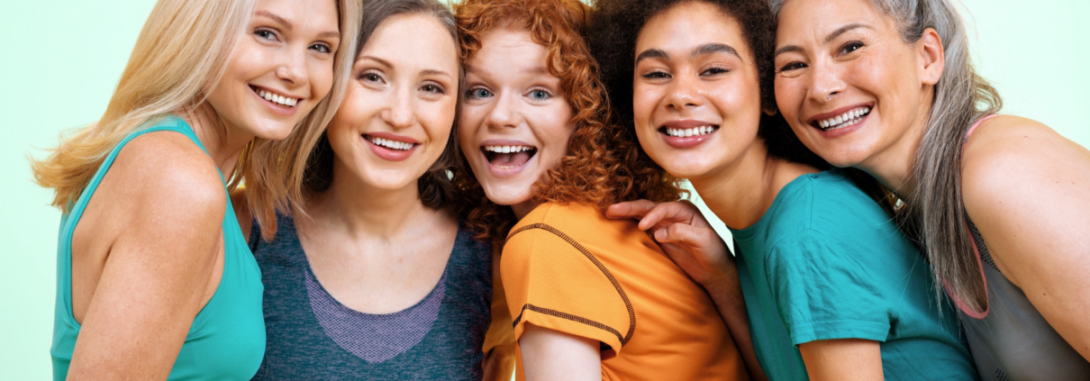 5 ethinically diverse women in their 40s and 50s lean toward each other and pose, smiling, for the camera.