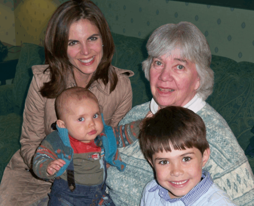 Journalist Natalie Morales sits on a green couch with her mother-in-law and Natalie's two children when they were still young. One is a baby and another is about 6.