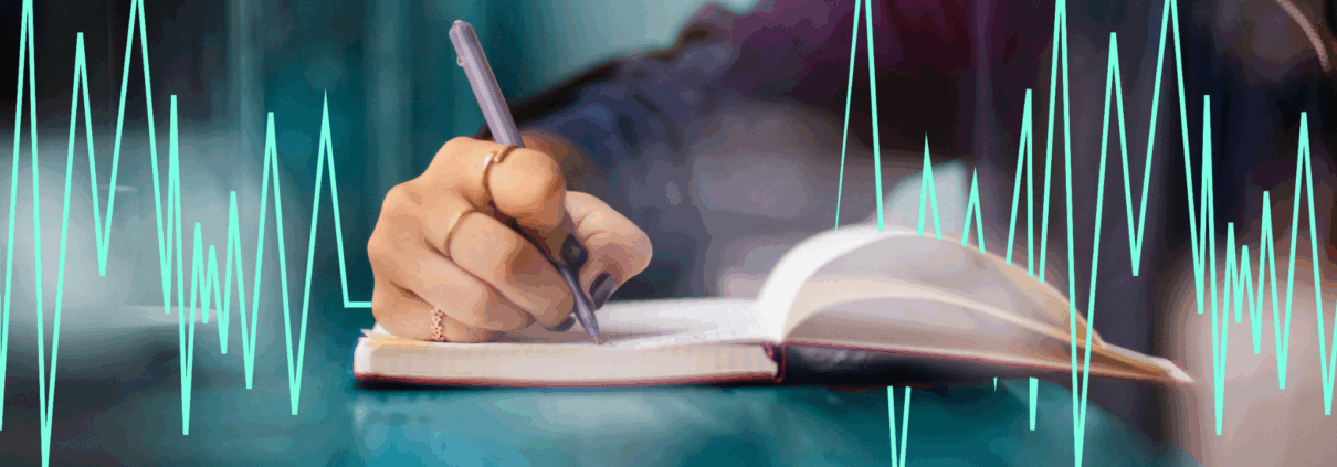 A white hand writes in a journal and a green heart rhythm image goes across the page.