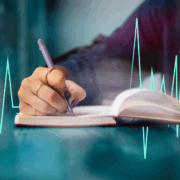 A white hand writes in a journal and a green heart rhythm image goes across the page.