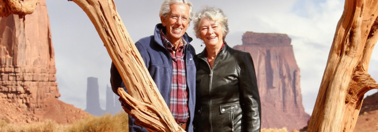 Jim and Geri Taylor stand in the desert in the U.S. West and pose and smile for the camera.