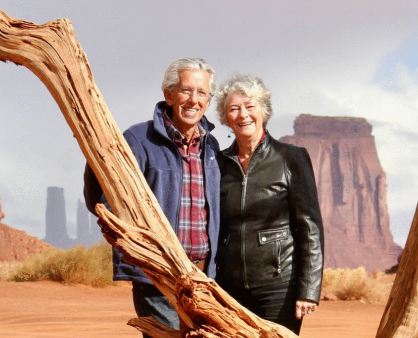 Jim and Geri Taylor stand in the desert in the U.S. West and pose and smile for the camera.